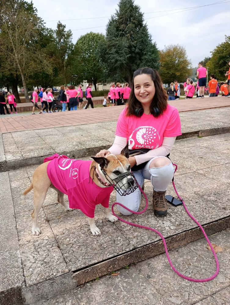 Charlène accroupie à côté de Joyce, muselée et en t-shirt rose, lors d'une marche Octobre Rose
